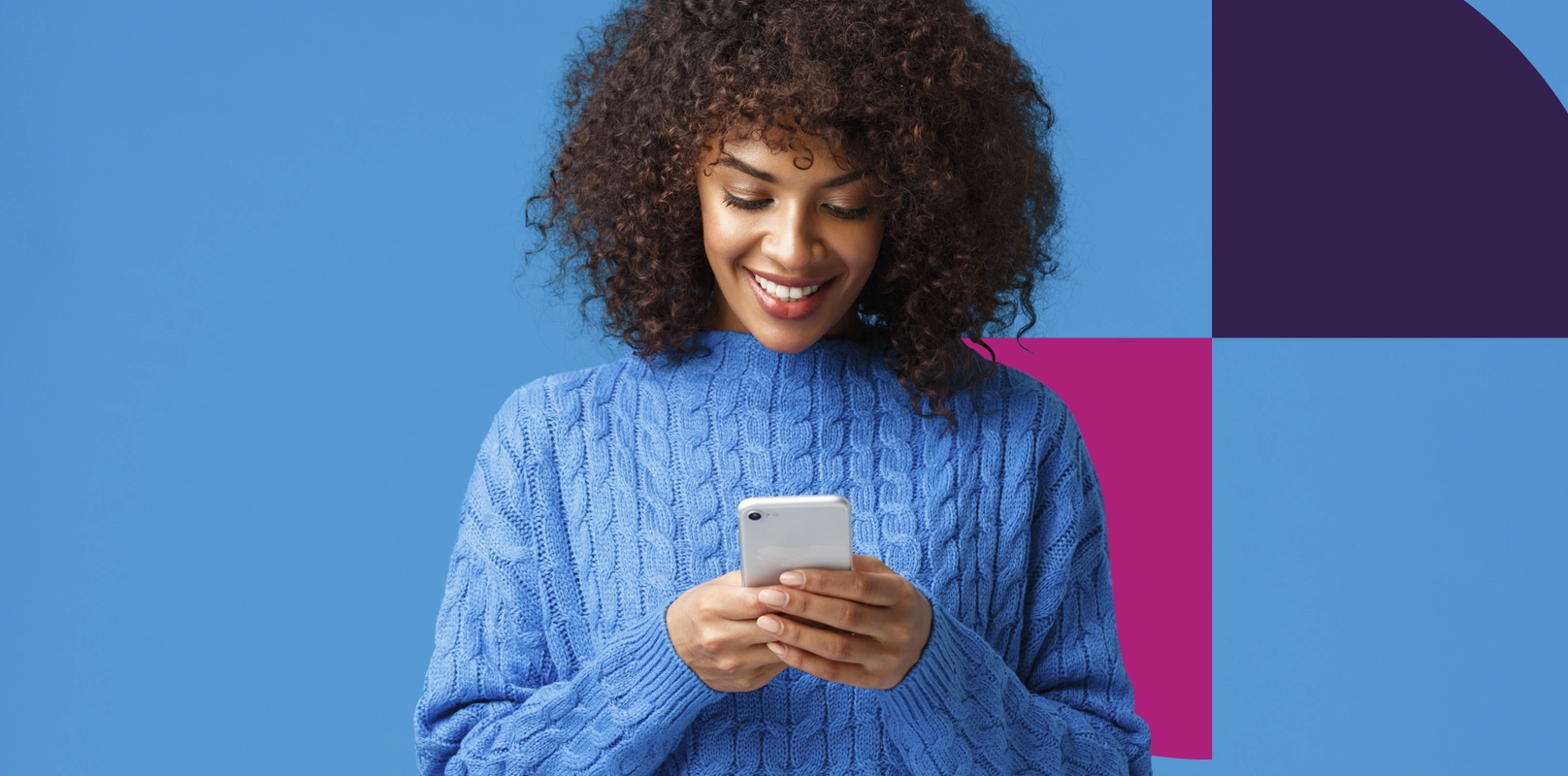 Smiling woman using mobile phone against blue background